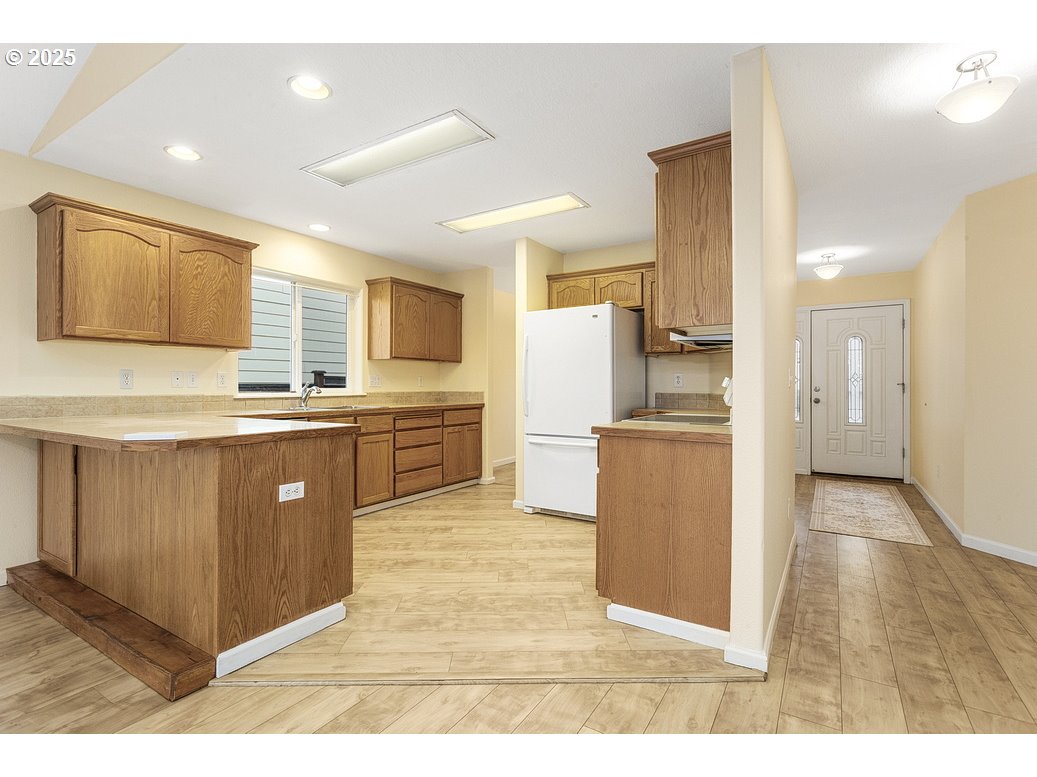 1575 Southeast Dexter Lane Gresham, OR 97080 - Photo 16 of 48 a kitchen with a sink a refrigerator and a stove top oven with wooden floor