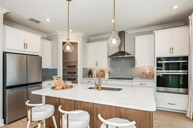 a kitchen with stainless steel appliances kitchen island granite countertop a dining table chairs and white cabinets