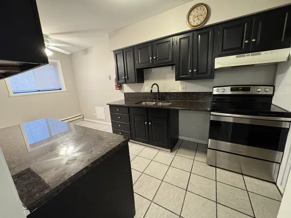 a kitchen with stainless steel appliances granite countertop a stove a sink and a microwave