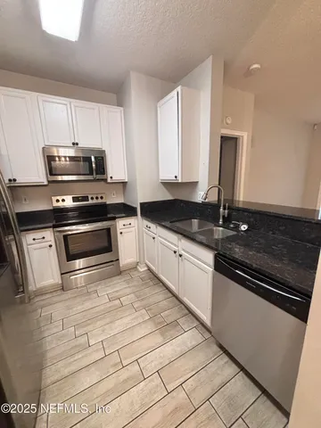 a kitchen with granite countertop a stove sink and microwave