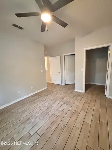 an empty room with wooden floor closet and fan