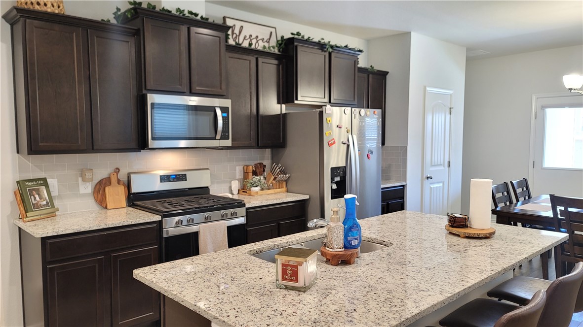 7633 Shadow Rider Lane Corpus Christi, TX 78414 - Photo 8 of 23 a kitchen with granite countertop stainless steel appliances a stove refrigerator sink and microwave