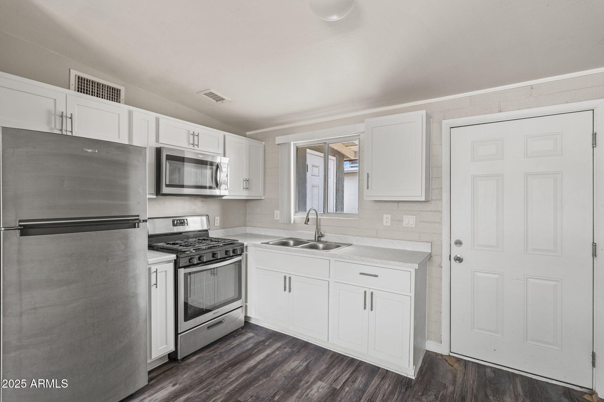 221 5th Avenue East, Unit 225 Buckeye, AZ 85326 - Photo 8 of 14 a kitchen with white cabinets and white appliances