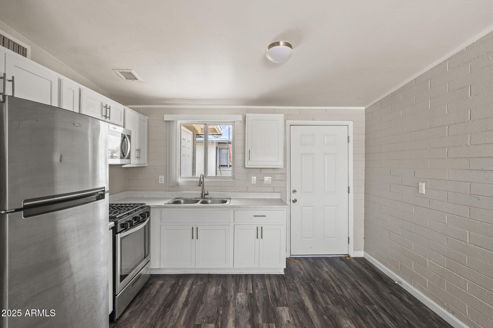 221 5th Avenue East, Unit 225 Buckeye, AZ 85326 - Photo 9 of 14 a kitchen with a refrigerator a sink and dishwasher a stove with wooden floor