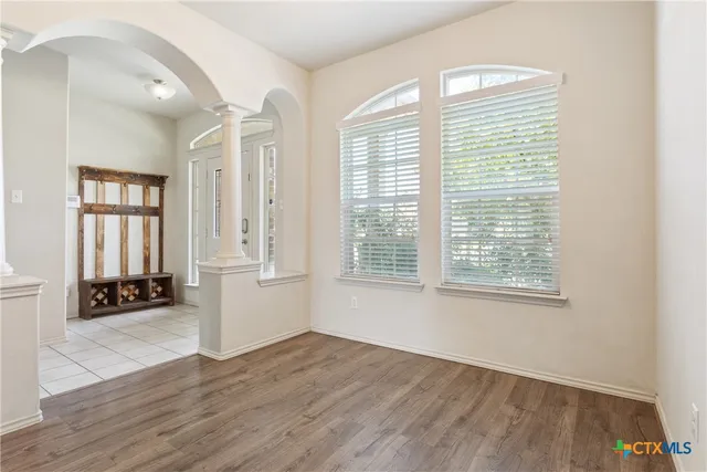 a view of an empty room with a window and wooden floor