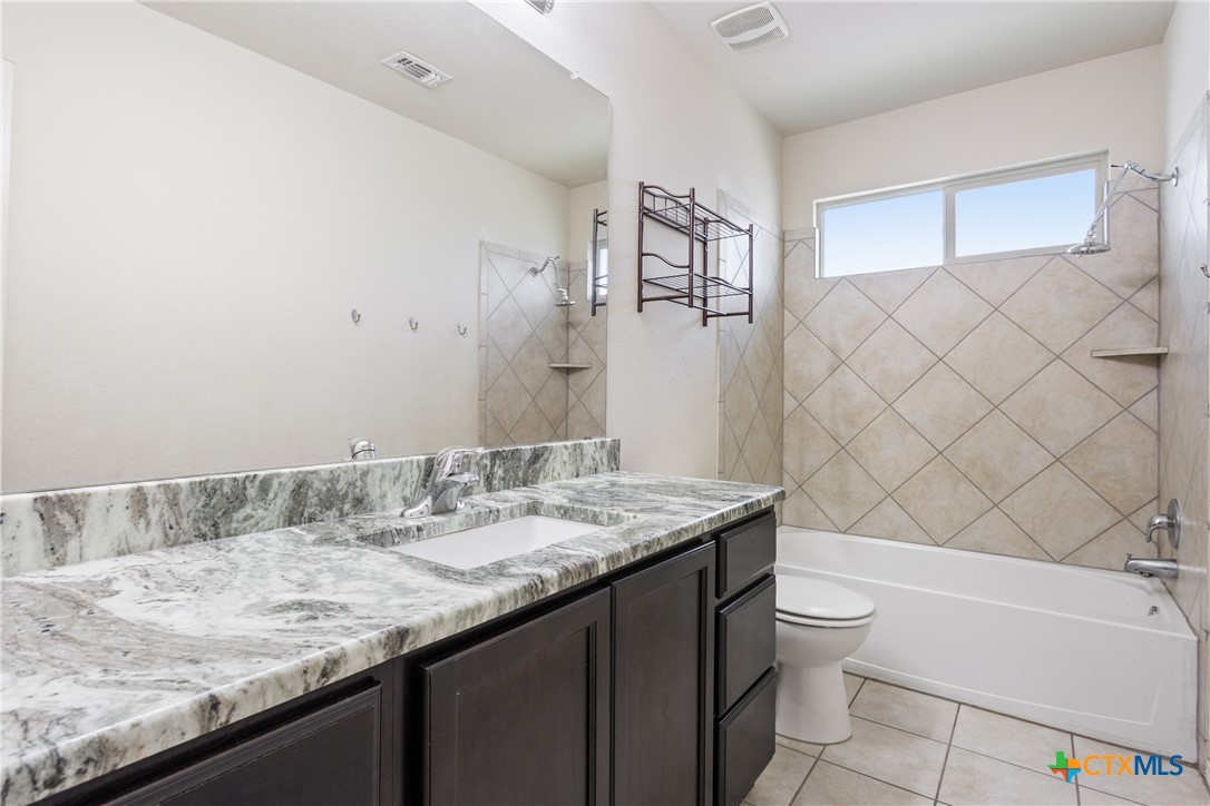 231 Druse Lane Jarrell, TX 76537 - Photo 22 of 38 a bathroom with a granite countertop sink a toilet and bathtub