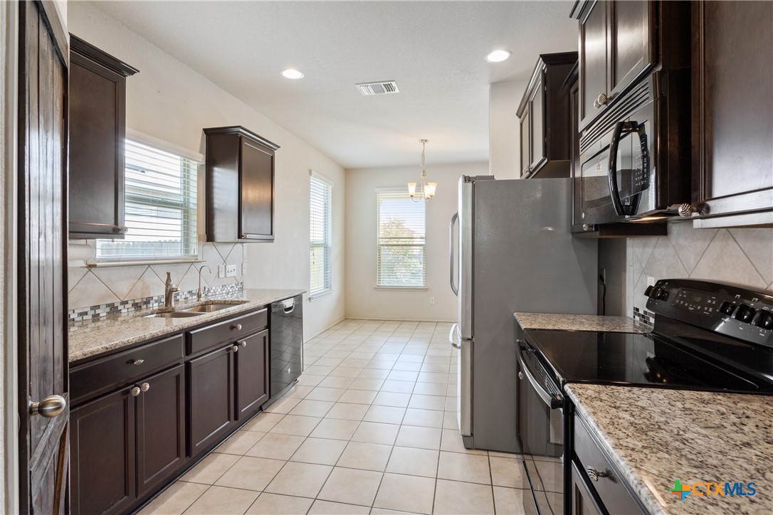 231 Druse Lane Jarrell, TX 76537 - Photo 9 of 38 a kitchen with stainless steel appliances granite countertop a sink stove and refrigerator
