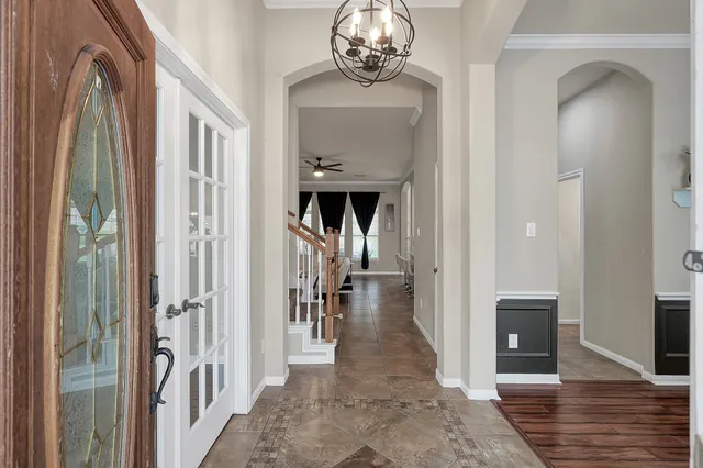 a view of a hallway with wooden floor and a chandelier