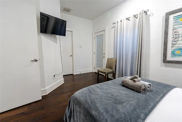a bedroom with a large bed and a flat tv screen on a dresser
