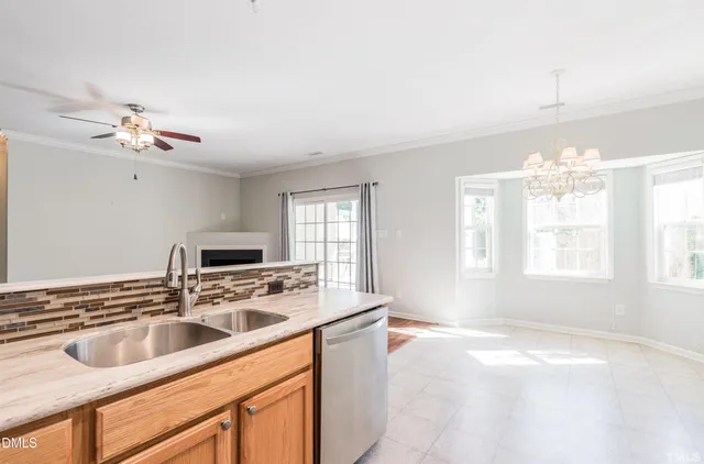 a kitchen with stainless steel appliances a sink a stove a microwave a dining table and chairs