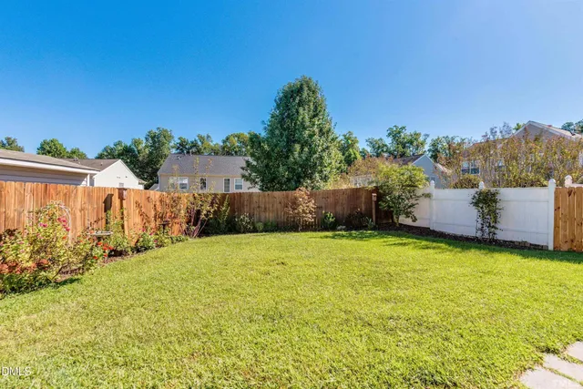 a backyard of a house with plants and wooden fence