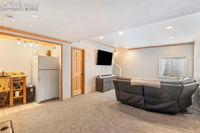 a living room with furniture a flat screen tv and a refrigerator