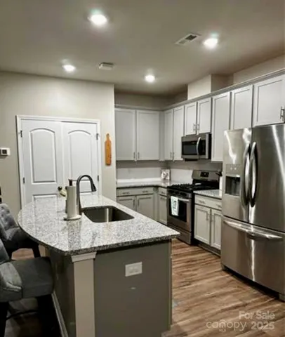 a kitchen with kitchen island granite countertop a sink counter space appliances and cabinets