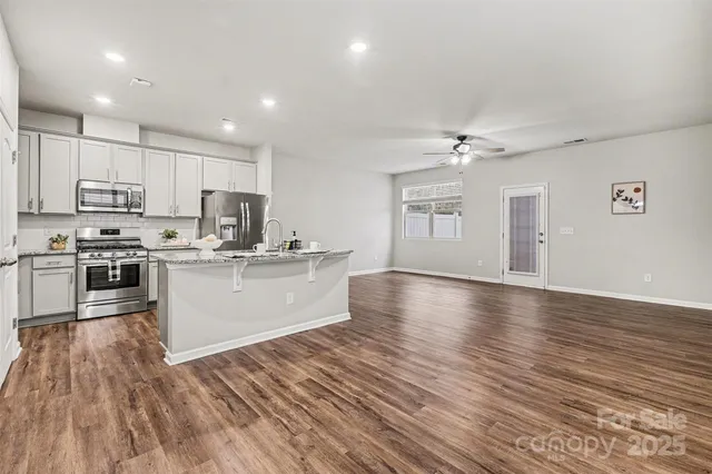 a view of a hallway with wooden floor and a bathroom