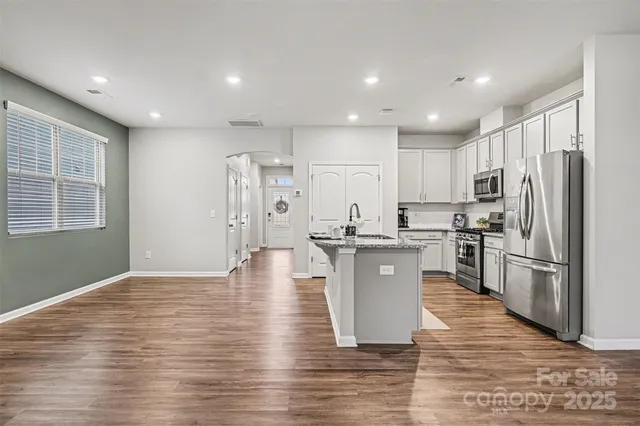 a view of a hallway with wooden floor and a bathroom