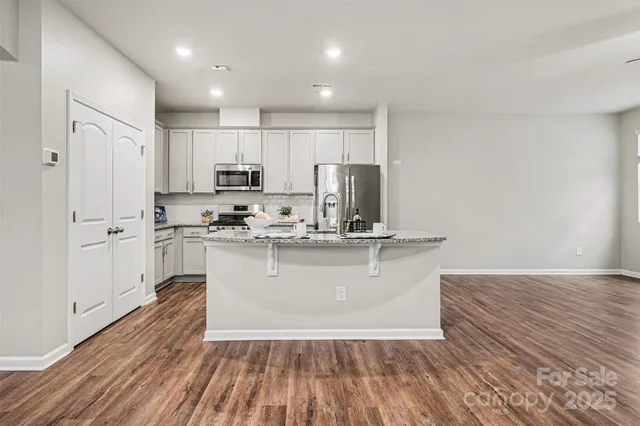 a kitchen with stainless steel appliances granite countertop a sink a stove top oven a refrigerator with granite countertops and cabinets