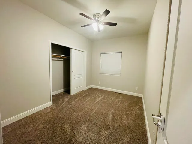 an empty room with closet and a ceiling fan