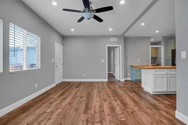 a view of an empty room with window and wooden floor