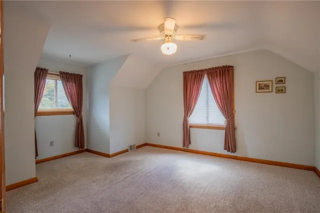an empty room with chandelier fan and windows