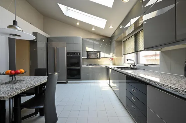 a large kitchen with granite countertop lots of counter top space and stainless steel appliances