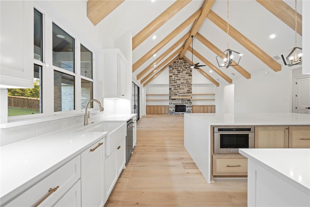 108 Bel Grand Road Haslet, TX 76052 - Photo 40 of 40 Kitchen with a large fireplace, light stone counters, open floor plan, beam ceiling, and light wood-style floors