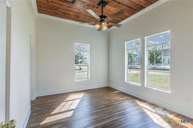 a view of a livingroom with a fan a large window with wooden floor