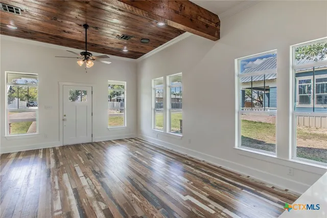 an empty room with wooden floor windows and windows