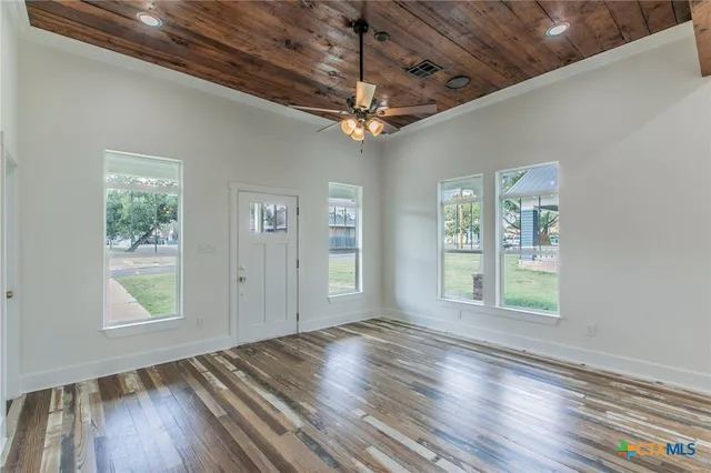 an empty room with wooden floor chandelier and windows