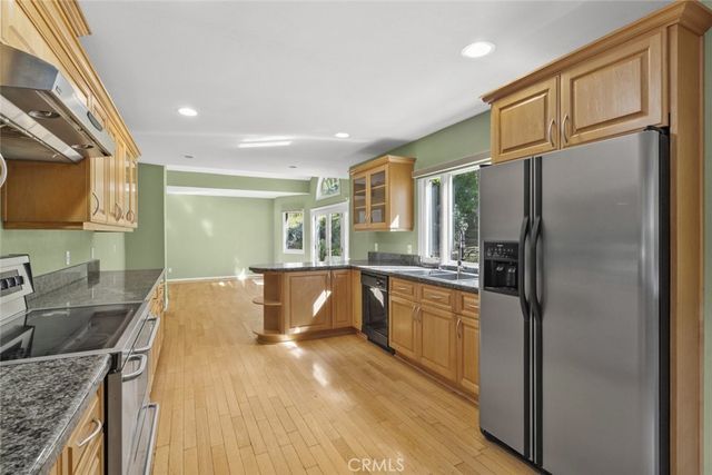 a kitchen with stainless steel appliances granite countertop a sink refrigerator and cabinets