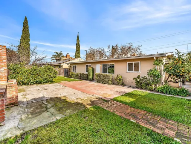 a view of a house with a yard and potted plants