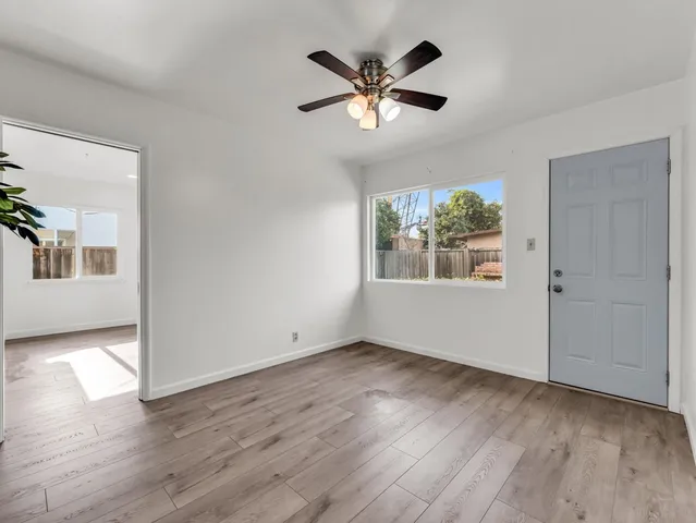 a view of an empty room with wooden floor and a window