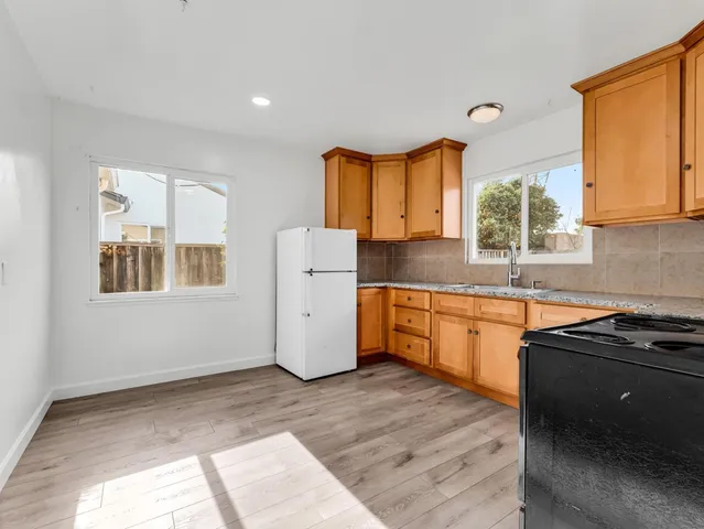 a kitchen with a window wooden cabinets and a stove top oven