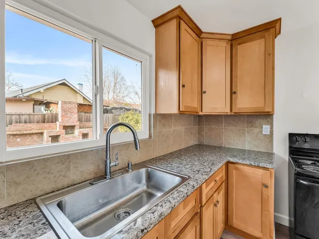 a kitchen with granite countertop a sink a counter top space and stainless steel appliances