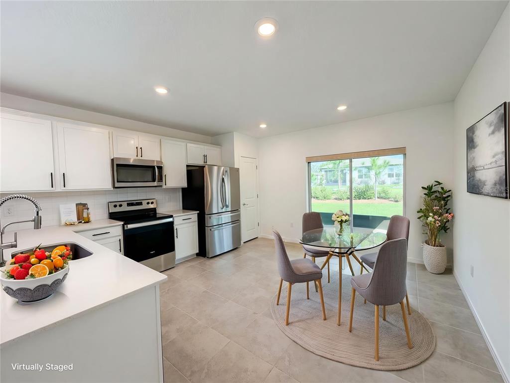 8359 Southwest 54th Street Ocala, FL 34481 - Photo 9 of 26 a kitchen with stainless steel appliances kitchen island granite countertop a refrigerator a stove top oven a sink dishwasher and white cabinets with wooden floor