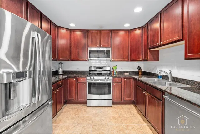 a kitchen with stainless steel appliances granite countertop a stove top oven a sink and dishwasher a refrigerator with wooden cabinets