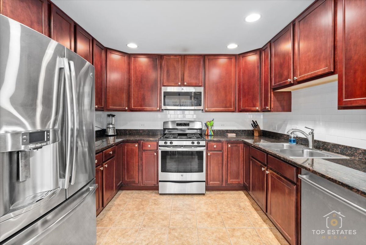 1651 Pauline Circle, Unit 1651 Mundelein, IL 60060 - Photo 16 of 42 a kitchen with stainless steel appliances granite countertop a stove top oven a sink and dishwasher a refrigerator with wooden cabinets