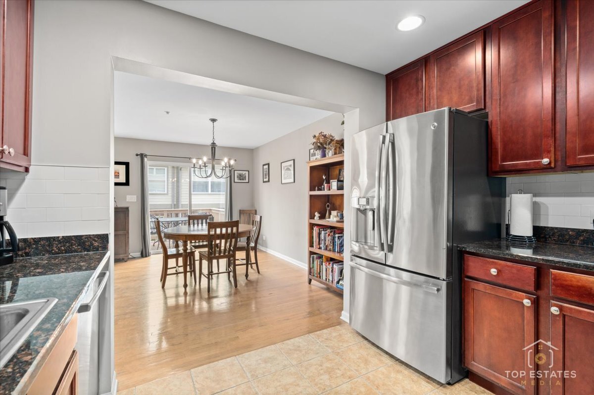 1651 Pauline Circle, Unit 1651 Mundelein, IL 60060 - Photo 18 of 42 a kitchen with granite countertop stainless steel appliances a refrigerator a stove a dining table and chairs with wooden floor