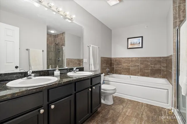 a bathroom with a double vanity sink toilet mirror and bathtub