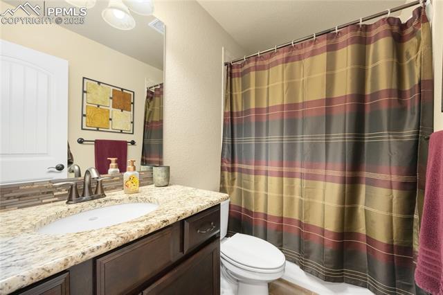 1131 Old North Gate Road Colorado Springs, CO 80921 - Photo 22 of 39 Full bath with vanity, a textured wall, and a shower with curtain