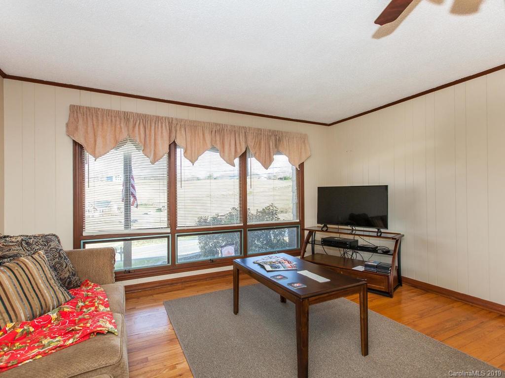 2533 Iron Duff Road Waynesville, NC 28785 - Photo 12 of 35 a living room with furniture a flat screen tv and a floor to ceiling window