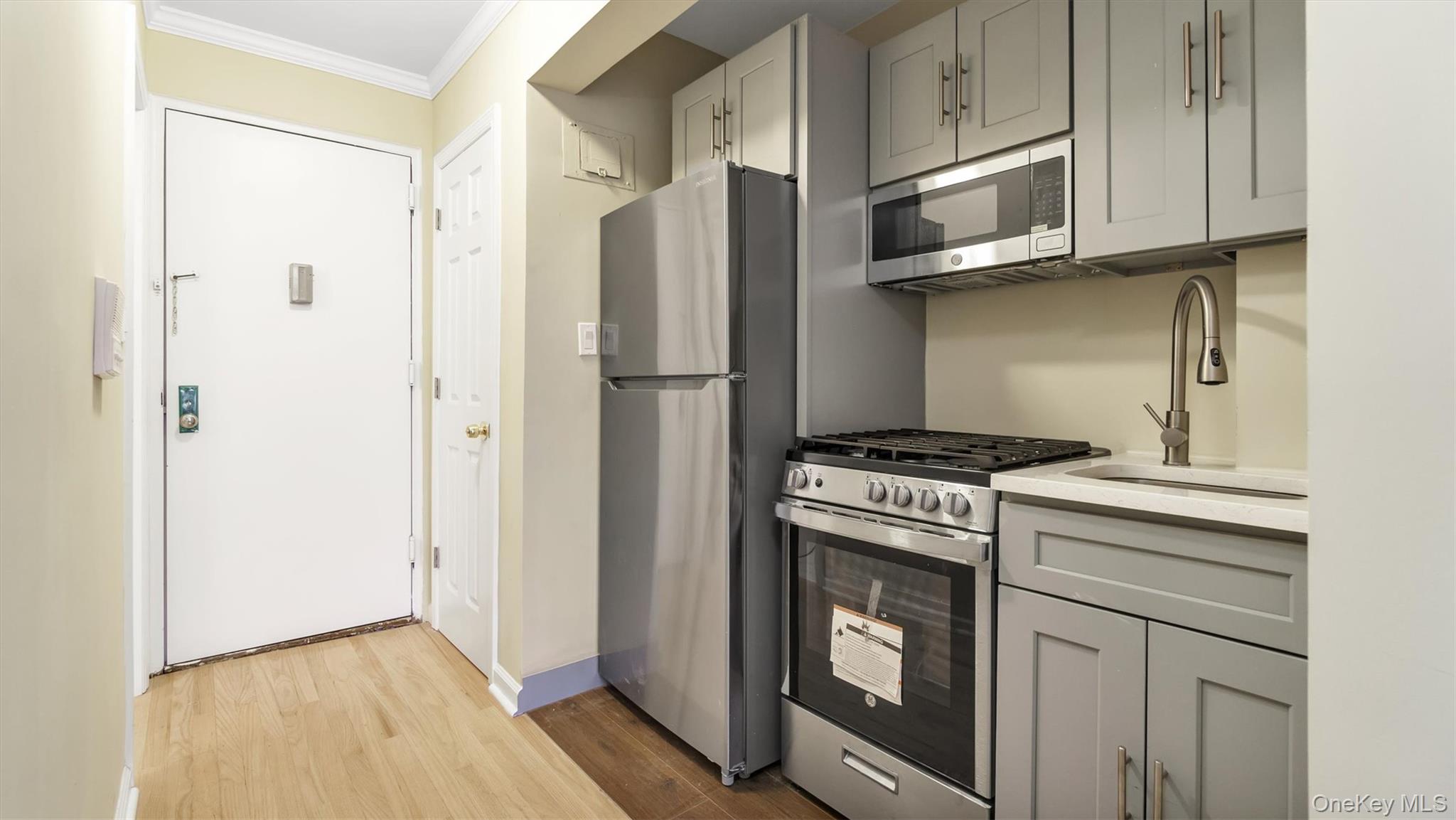 50-21 39th Place, Unit 2C Queens, NY 11104 - Photo 3 of 12 Kitchen featuring gray cabinets, crown molding, sink, and appliances with stainless steel finishes