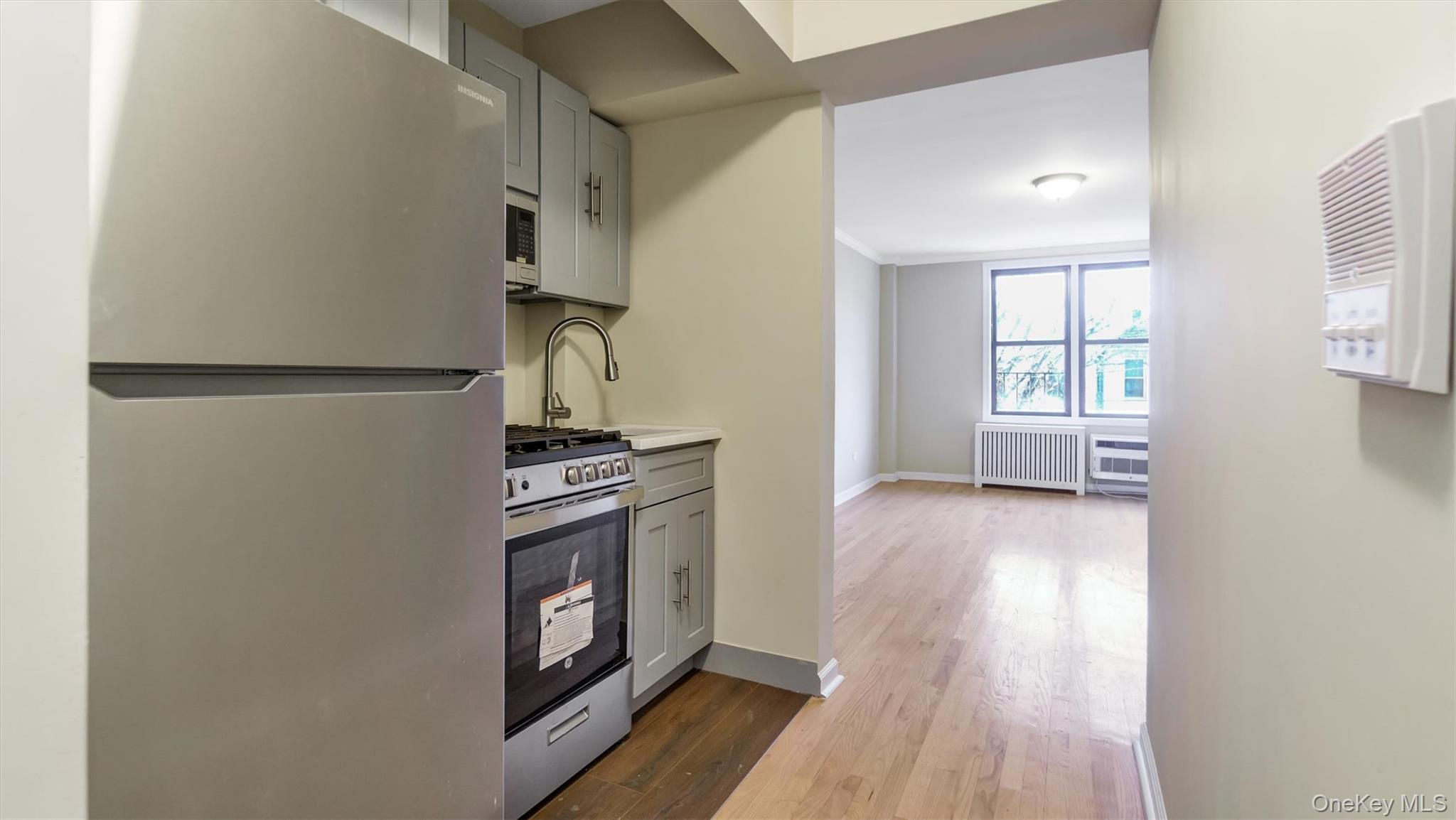 50-21 39th Place, Unit 2C Queens, NY 11104 - Photo 4 of 12 Kitchen with appliances with stainless steel finishes, crown molding, wood-type flooring, radiator heating unit, and gray cabinets