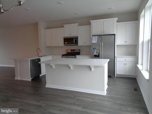 a kitchen with kitchen island a sink a stove a refrigerator and white cabinets