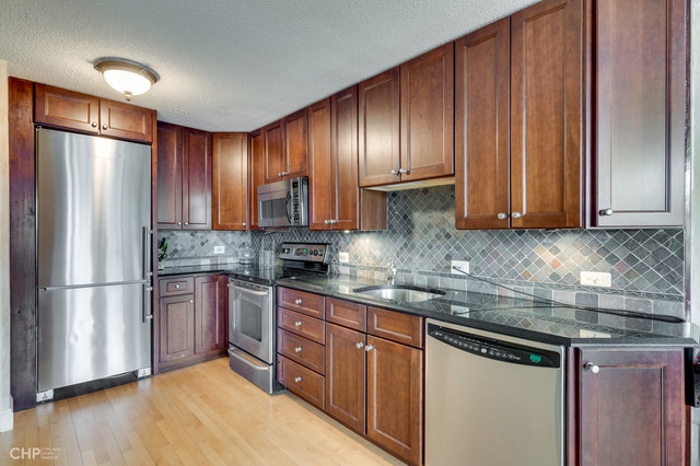 1030 North State Street, Unit 13D Chicago, IL 60610 - Photo 4 of 12 a kitchen with stainless steel appliances granite countertop a refrigerator a sink dishwasher a stove and a microwave oven on granite countertops