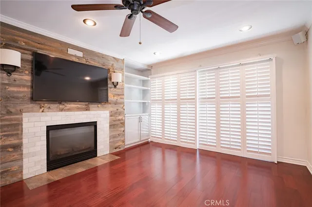 a view of a livingroom with a fireplace a ceiling fan and wooden floor