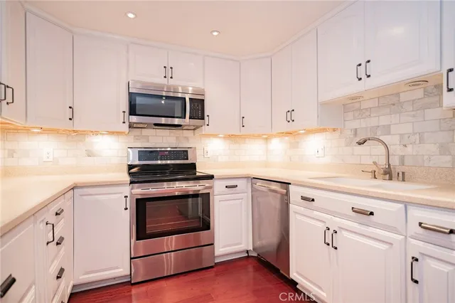 a kitchen with white cabinets and appliances