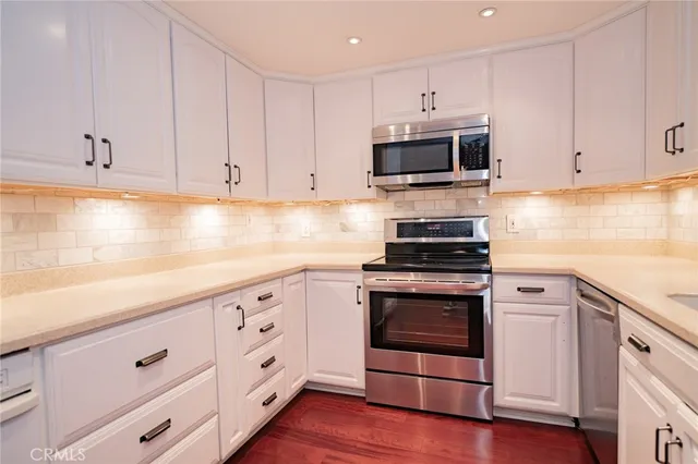 a kitchen with white cabinets and appliances