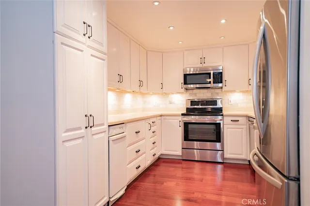 a kitchen with granite countertop white cabinets and stainless steel appliances