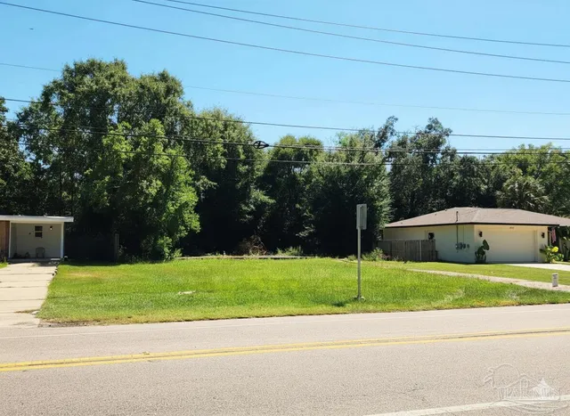 a view of a house with a yard and large trees