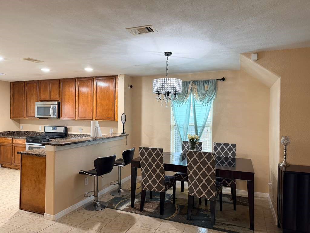 931 Salado Slough Lane Rosenberg, TX 77471 - Photo 12 of 17 a kitchen with granite countertop a dining table chairs and white cabinets